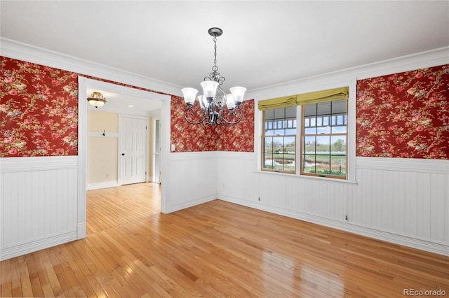 6231 Prospect Rd, Longmont, CO 80503 - spare room with wainscoting, a chandelier, wallpapered walls, and light wood-style floors