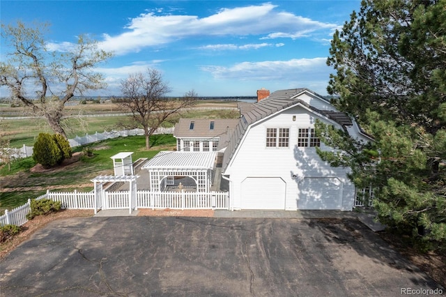 6231 Prospect Rd, Longmont, CO 80503 - view of front of house with a gambrel roof, a fenced front yard, a garage, asphalt driveway, and a chimney