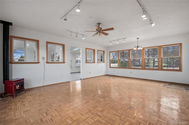 6231 Prospect Rd, Longmont, CO 80503 - unfurnished living room with rail lighting, a wood stove, baseboards, and a textured ceiling
