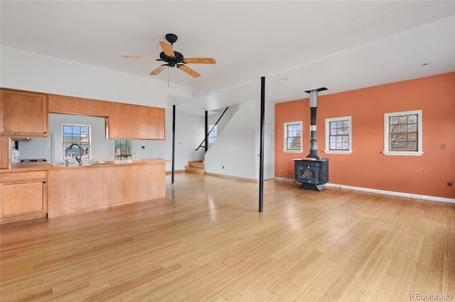 6231 Prospect Rd, Longmont, CO 80503 - unfurnished living room with a sink, a wood stove, light wood finished floors, stairway, and a ceiling fan