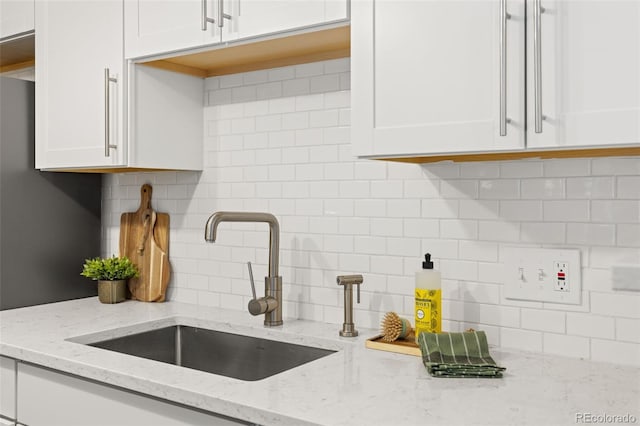 8335 Fairmount Dr Unit 208, Denver, CO 80247 - kitchen with white cabinets, tasteful backsplash, and light stone countertops
