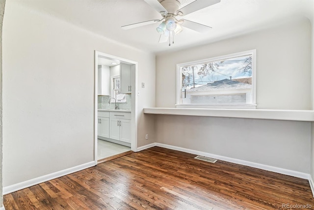 spare room featuring baseboards, visible vents, ceiling fan, wood finished floors, and a sink