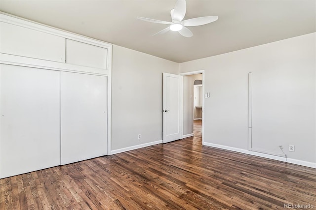 unfurnished bedroom featuring arched walkways, a closet, a ceiling fan, wood finished floors, and baseboards