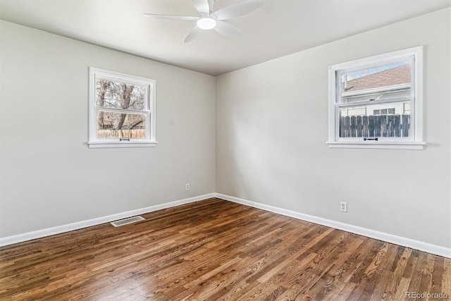 empty room featuring a ceiling fan, visible vents, baseboards, and wood finished floors