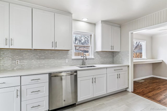 kitchen with a sink, white cabinetry, light countertops, and stainless steel dishwasher