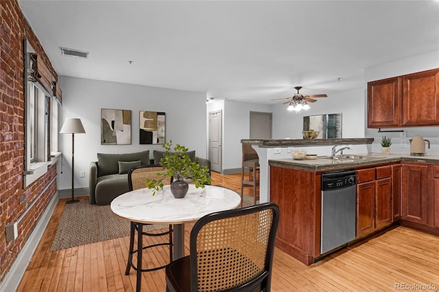 3211 Zuni St Unit 14, Denver, CO 80211 - kitchen with stainless steel dishwasher, brick wall, a peninsula, a sink, and light wood-style floors