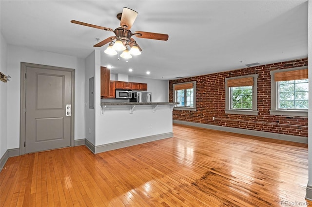 3211 Zuni St Unit 14, Denver, CO 80211 - unfurnished living room featuring brick wall, baseboards, light wood finished floors, and a ceiling fan