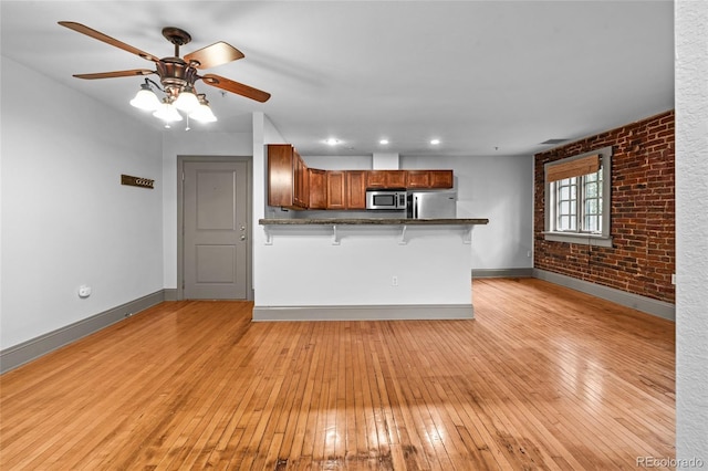 3211 Zuni St Unit 14, Denver, CO 80211 - kitchen featuring stainless steel appliances, a peninsula, a kitchen bar, light wood-style floors, and dark countertops