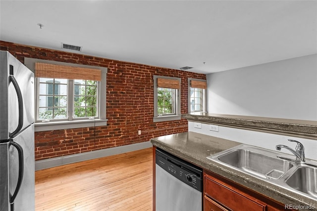 3211 Zuni St Unit 14, Denver, CO 80211 - kitchen featuring appliances with stainless steel finishes, a sink, dark countertops, light wood-type flooring, and brick wall