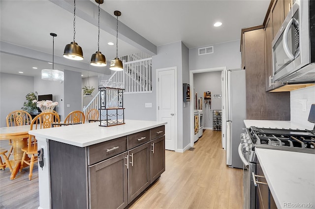 kitchen with pendant lighting, light hardwood / wood-style flooring, dark brown cabinets, stainless steel appliances, and tasteful backsplash