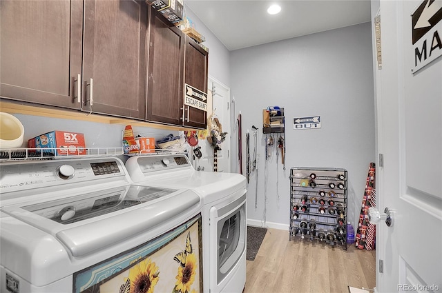 laundry area with light hardwood / wood-style flooring, washer and clothes dryer, and cabinets