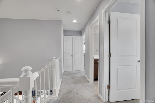 hallway with light carpet and an upstairs landing