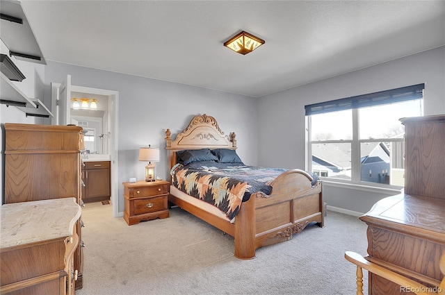bedroom with baseboards, light carpet, and ensuite bath