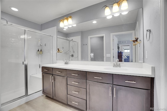 ensuite bathroom featuring double vanity, visible vents, a shower stall, and a sink