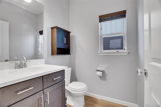 bathroom with baseboards, vanity, toilet, and wood finished floors