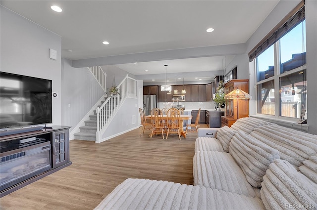 living room with light wood-style floors, recessed lighting, baseboards, and stairway