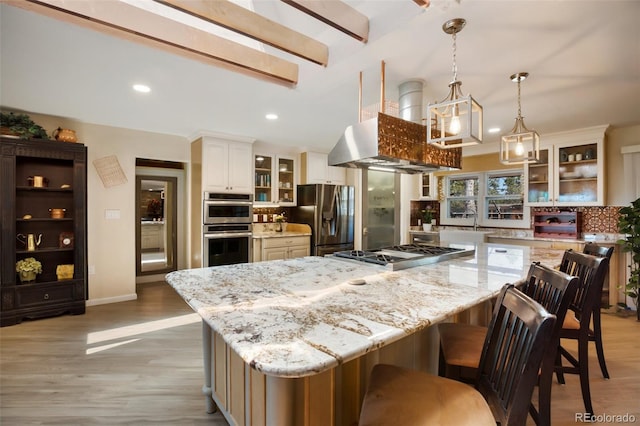 kitchen featuring light stone counters, a spacious island, decorative light fixtures, and appliances with stainless steel finishes