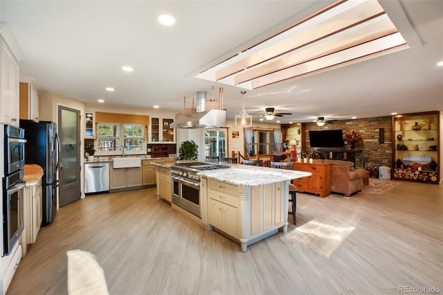 kitchen with pendant lighting, a center island, sink, light stone counters, and stainless steel appliances