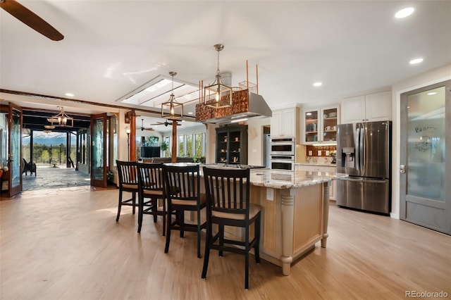 kitchen featuring white cabinetry, ceiling fan, a center island, and stainless steel refrigerator with ice dispenser