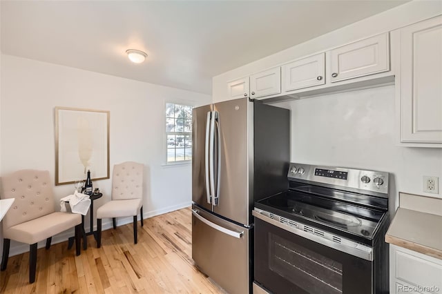 kitchen with white cabinets, appliances with stainless steel finishes, and light hardwood / wood-style flooring