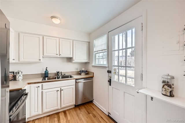 kitchen with sink, white cabinets, appliances with stainless steel finishes, and light wood-type flooring