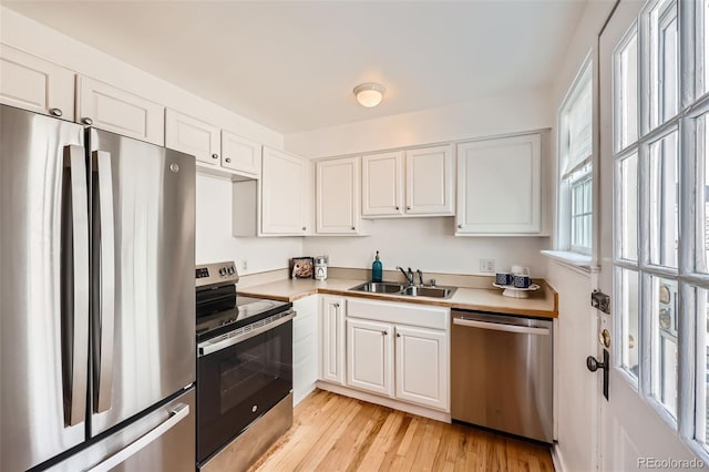 kitchen with sink, stainless steel appliances, light hardwood / wood-style flooring, and white cabinets