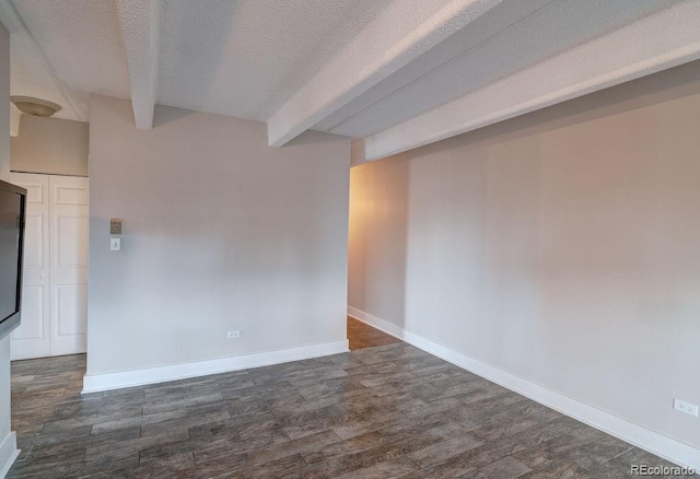 spare room with beam ceiling, dark hardwood / wood-style flooring, and a textured ceiling