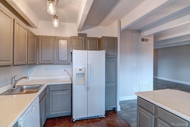 kitchen featuring a textured ceiling, white appliances, sink, and hanging light fixtures