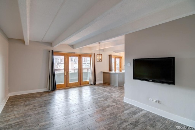 unfurnished living room with a chandelier, hardwood / wood-style flooring, and beamed ceiling