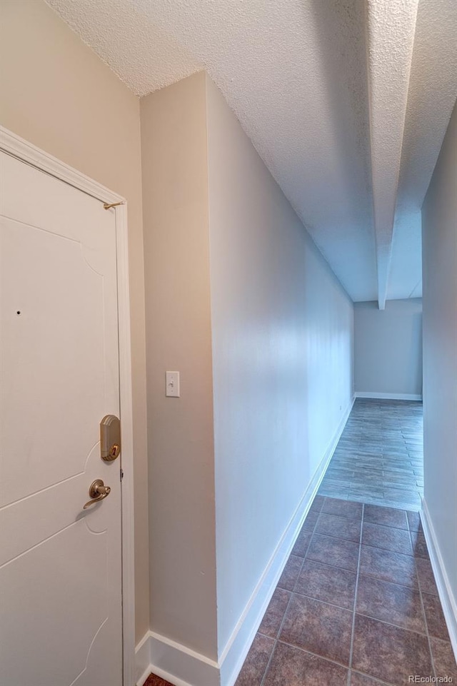 hall featuring dark tile patterned floors and a textured ceiling