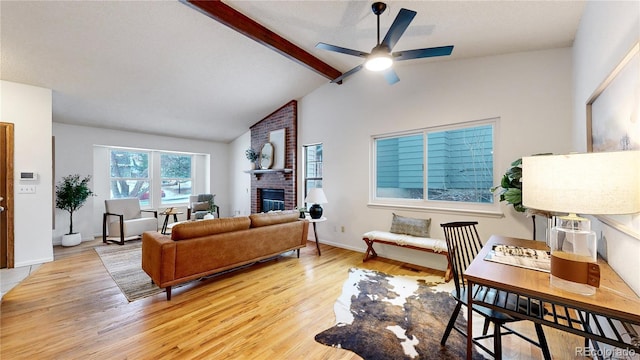 living room with ceiling fan, vaulted ceiling with beams, a fireplace, and light hardwood / wood-style flooring