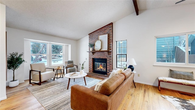 living room featuring hardwood / wood-style floors, a textured ceiling, a fireplace, and beamed ceiling