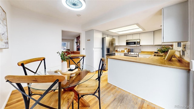 kitchen featuring stainless steel appliances, sink, kitchen peninsula, and light hardwood / wood-style floors