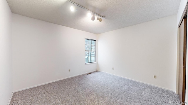 spare room with rail lighting, carpet, and a textured ceiling