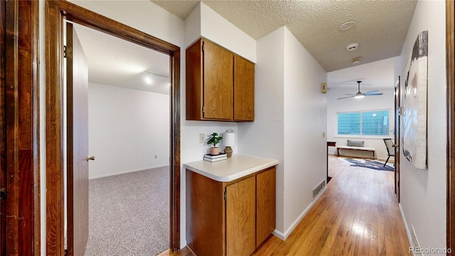 hall with light hardwood / wood-style flooring and a textured ceiling