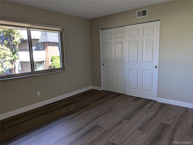 unfurnished bedroom featuring dark wood-type flooring and a closet