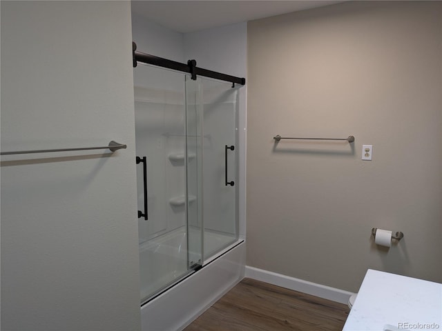 bathroom with hardwood / wood-style flooring and shower / bath combination with glass door