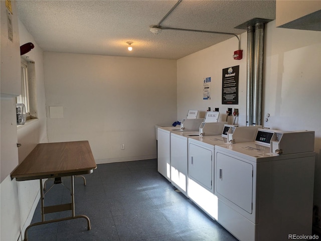 clothes washing area with washer and dryer and a textured ceiling