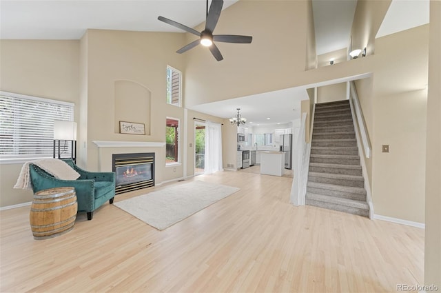 3565 W 112th Cir, Westminster, CO 80031 - unfurnished living room featuring baseboards, stairway, a glass covered fireplace, light wood-style floors, and a chandelier