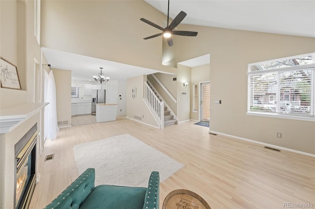3565 W 112th Cir, Westminster, CO 80031 - living room with a glass covered fireplace, a chandelier, high vaulted ceiling, stairway, and light wood-style floors