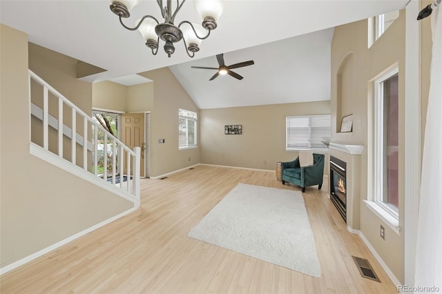 3565 W 112th Cir, Westminster, CO 80031 - unfurnished living room featuring stairway, light wood-type flooring, a ceiling fan, a glass covered fireplace, and high vaulted ceiling