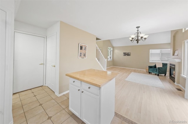 3565 W 112th Cir, Westminster, CO 80031 - kitchen with wood counters, a chandelier, white cabinetry, open floor plan, and baseboards