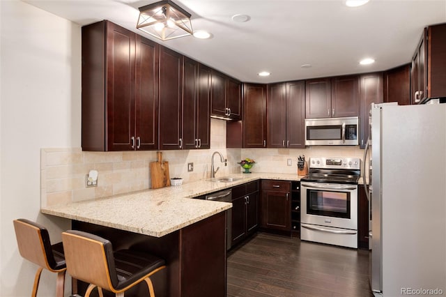 kitchen with decorative backsplash, appliances with stainless steel finishes, a peninsula, and a sink