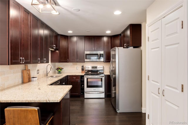 kitchen with dark wood finished floors, a sink, dark brown cabinetry, appliances with stainless steel finishes, and tasteful backsplash