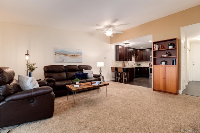 living room with baseboards, a ceiling fan, and carpet flooring