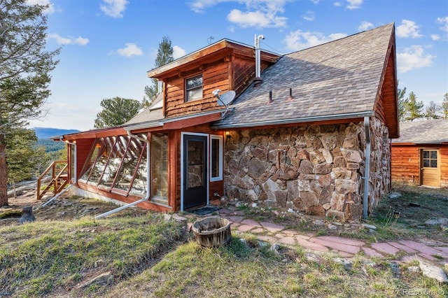 600 Rock Lake Rd, Ward, CO 80481 - back of house featuring stone siding, a sunroom, and roof with shingles