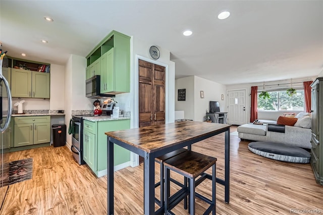 18662 E Brown Pl, Aurora, CO 80013 - kitchen with green cabinets, appliances with stainless steel finishes, light wood finished floors, recessed lighting, and open floor plan