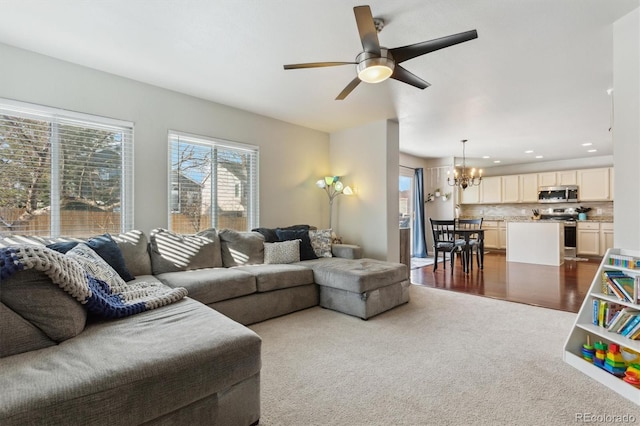 carpeted living room featuring ceiling fan with notable chandelier