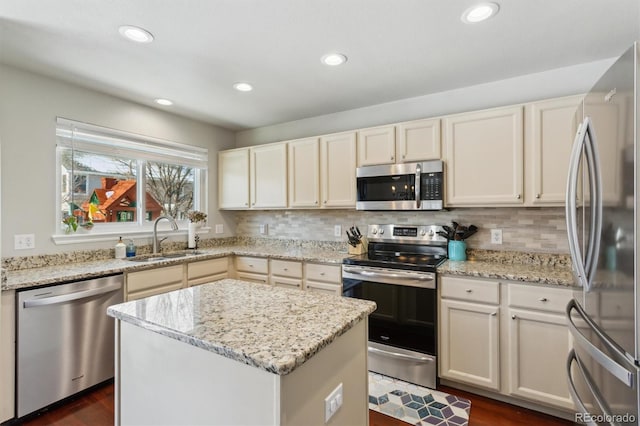 kitchen with sink, decorative backsplash, a center island, light stone counters, and stainless steel appliances