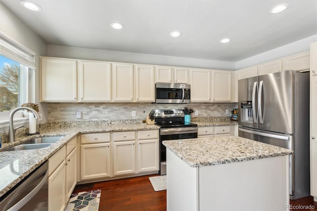 kitchen with appliances with stainless steel finishes, dark hardwood / wood-style floors, light stone countertops, and sink